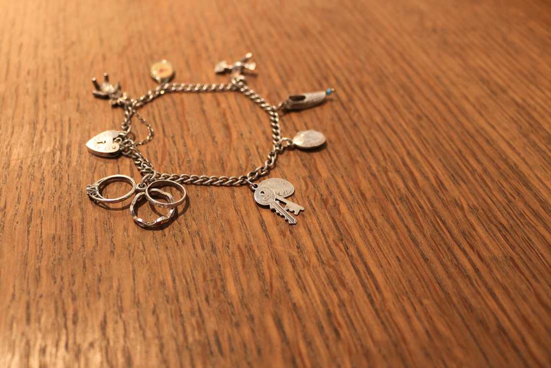 A charm bracelet lies on a wooden table A charm bracelet lies on a wooden table