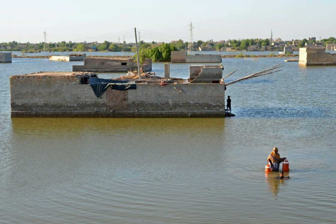 A woman wades through the flood waters to get drinking water in Dera Allah Yar, Pakistan; fossil fuel usage is a major contributor to climate change A woman wades through the flood waters to get drinking water in Dera Allah Yar, Pakistan; fossil fuel usage is a major contributor to climate change