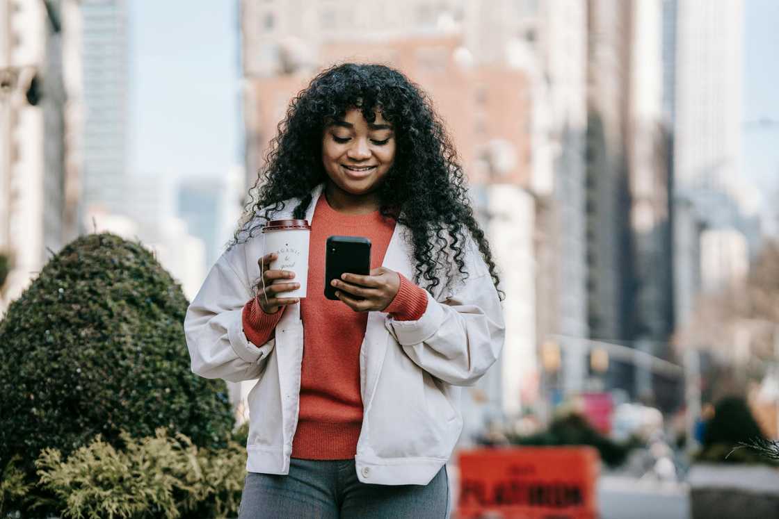 A cheerful woman typing something on a smartphone A cheerful woman typing something on a smartphone