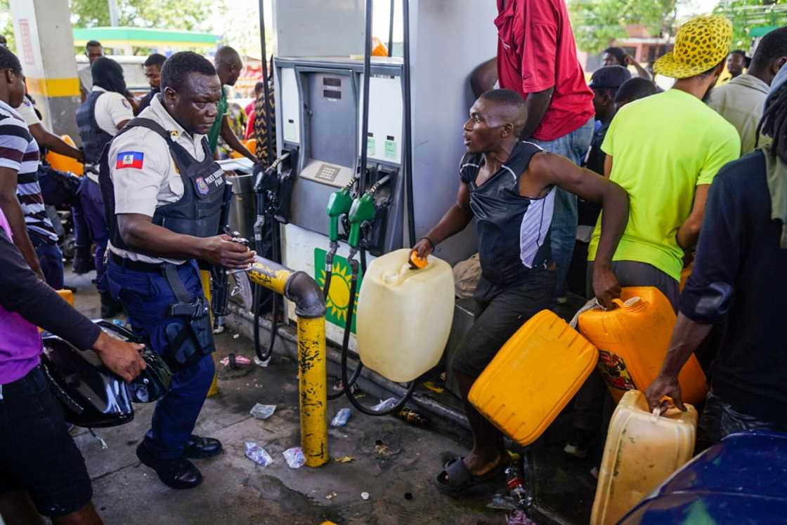A Haitian police officer confronts people queueing to collect petrol at a gas station in Port-au-Prince on July 15, 2022 A Haitian police officer confronts people queueing to collect petrol at a gas station in Port-au-Prince on July 15, 2022