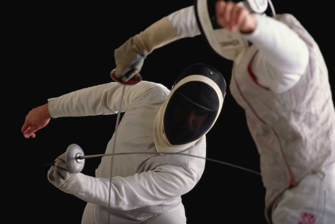 A fencing match between two competitors, both in fencing gear. A fencing match between two competitors, both in fencing gear.