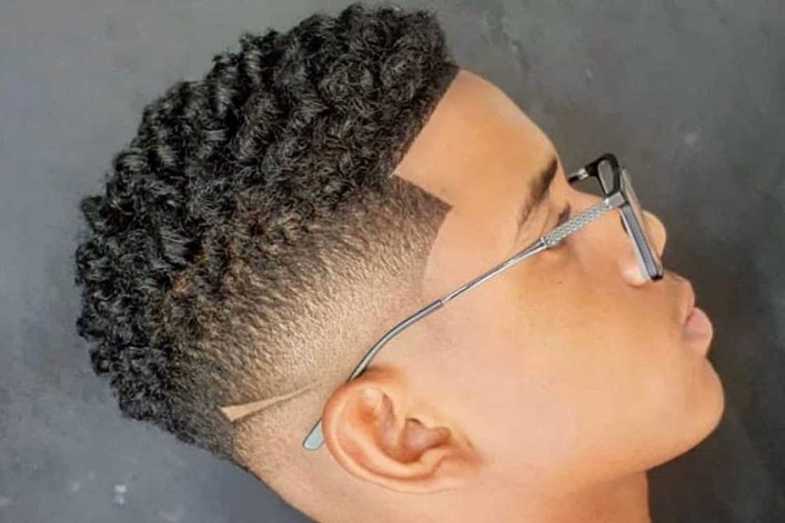 A man with a short curly hair and mid fade style