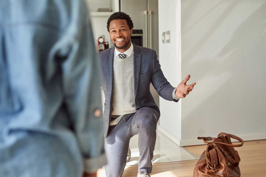 A cheerful young businessman kneeling on the ground.