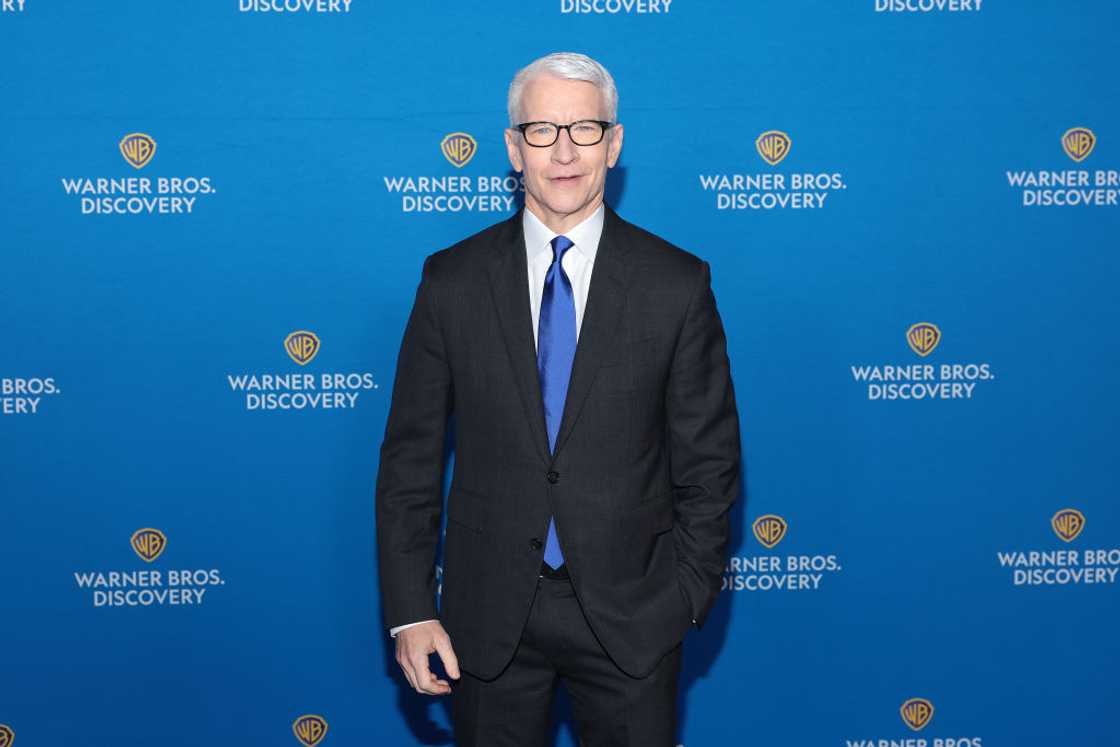 Anderson Cooper in black suit, white shirt, and blue tie