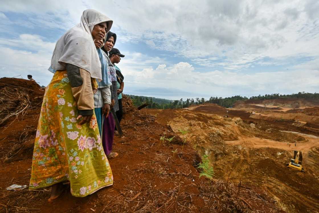 Royani (L) and others stand on their family land as they watch a nickel mining operation on Wawonii Royani (L) and others stand on their family land as they watch a nickel mining operation on Wawonii