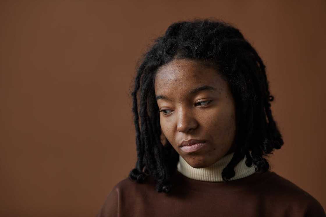 A woman with an expressionless face looks down.