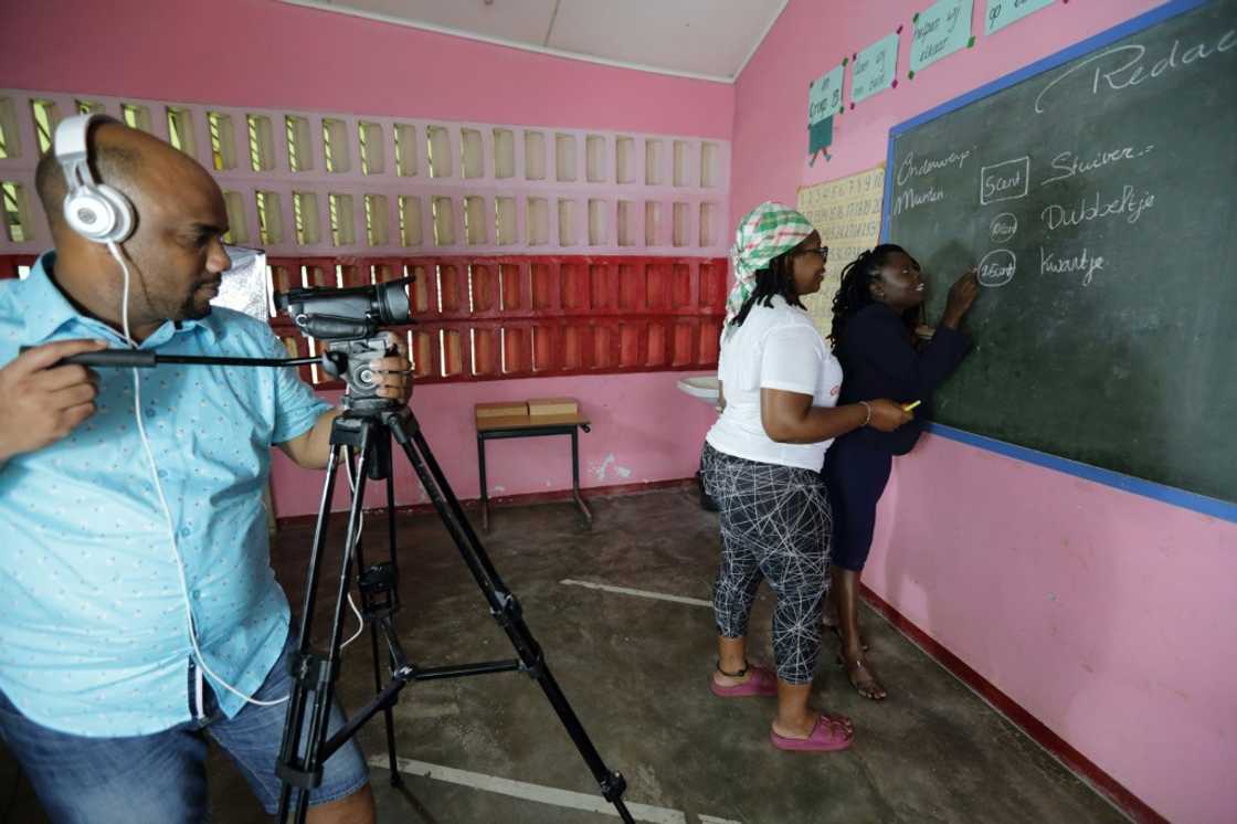 Soulamy Laurens (C) and other villagers who now live in the capital, prepare educational videos for children in flooded areas Soulamy Laurens (C) and other villagers who now live in the capital, prepare educational videos for children in flooded areas