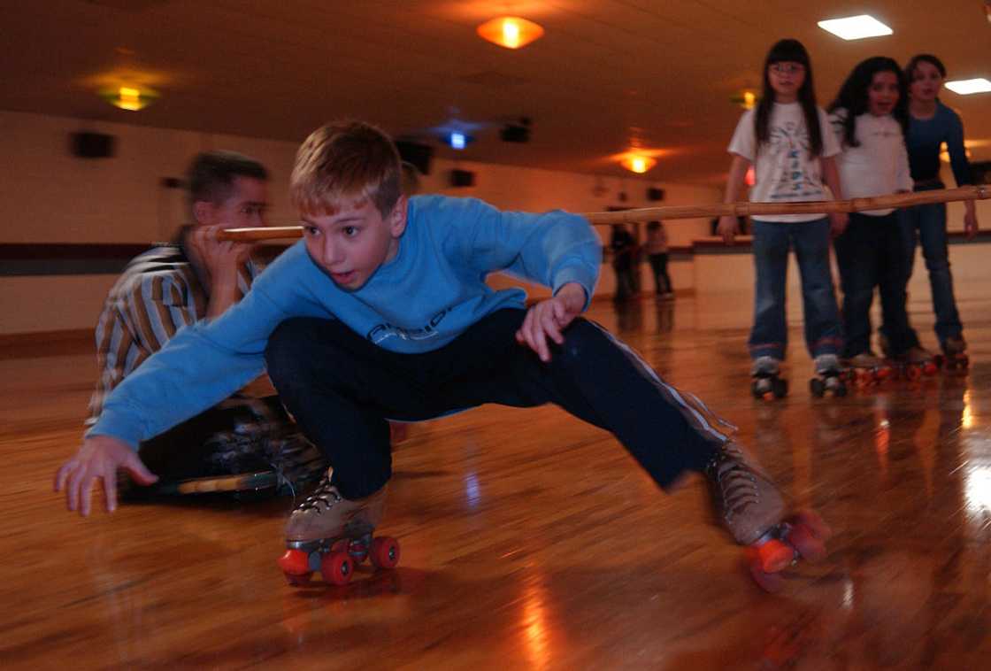 Sean M. Marsh ducks under a limbo pole during a game Sunday at the Fantasy Skating Center