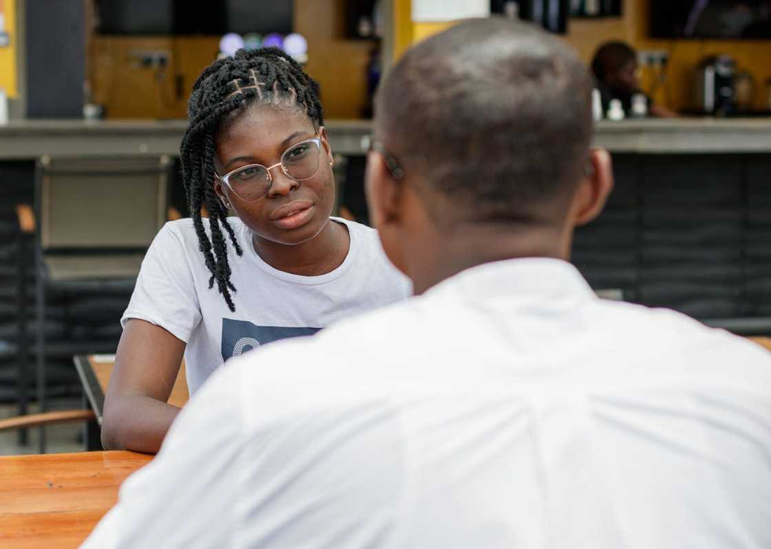 A woman listens intently while sitting across from a man at a table. A woman listens intently while sitting across from a man at a table.