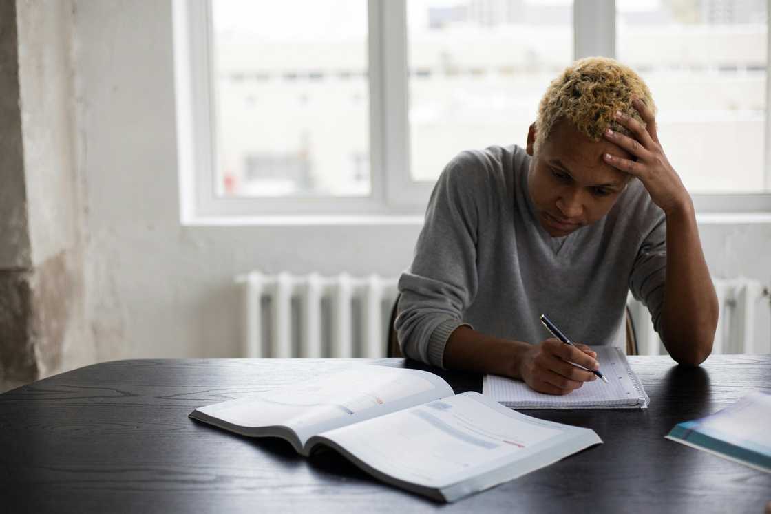 A young man writing on a notepad during a lesson A young man writing on a notepad during a lesson