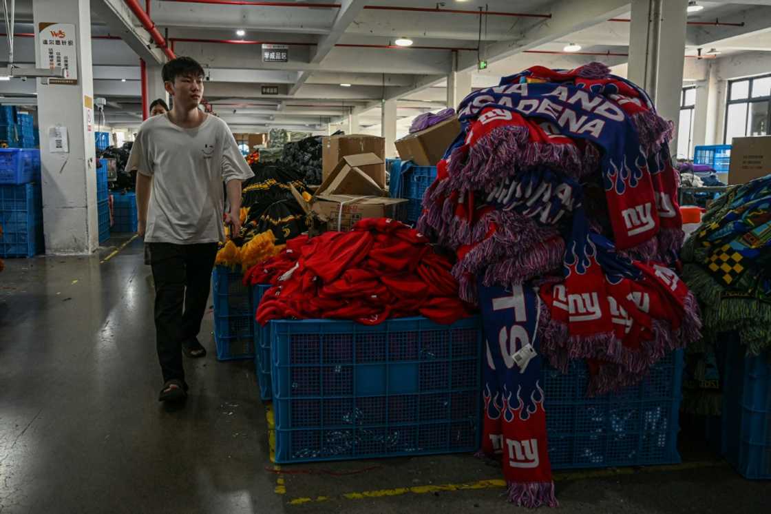 An employee walks past a pile of knitwear products at a factory that produces hats and scarves in Yiwu, in eastern China's Zhejiang province on September 18, 2025 An employee walks past a pile of knitwear products at a factory that produces hats and scarves in Yiwu, in eastern China's Zhejiang province on September 18, 2025