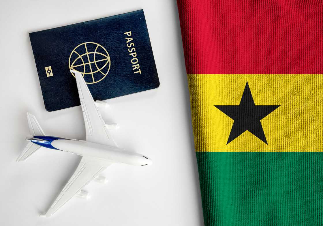 Flag of Ghana with passport and toy airplane