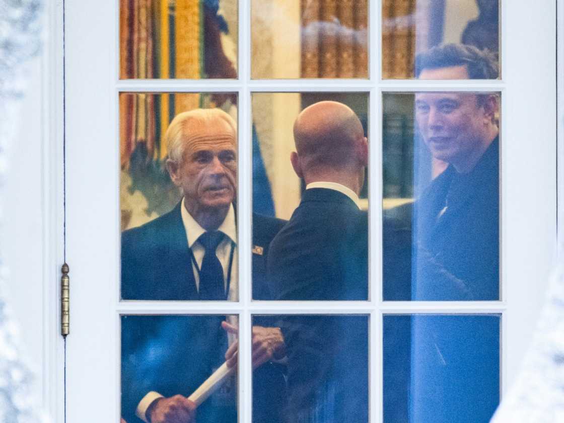 (FILES) (L-R) Senior Counselor to the President for Trade and Manufacturing, Peter Navarro, White House deputy chief of staff for policy and US homeland security advisor Stephen Miller, and Elon Musk speak inside the Oval Office of the White House before boarding Marine One with unseen US President Donald Trump in Washington, DC on March 14, 2025. Elon Musk on April 8 described Peter Navarro, a senior White House trade advisor, as "truly a moron" and "dumber than a sack of bricks" in a growing rift over Donald Trump's tariff policy. Musk, a key aide to the president, has signaled opposition to the tariffs, and the Tesla CEO hit out after Navarro described him as "not a car manufacturer" but "a car assembler."