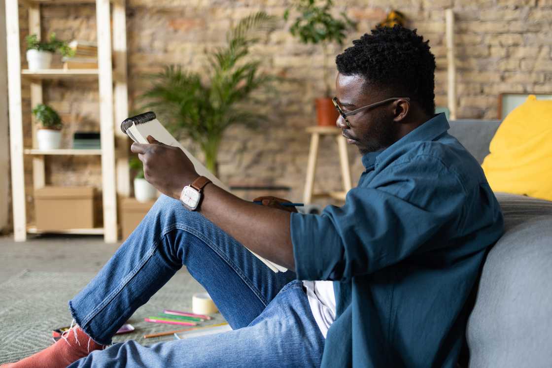 Person sketching quietly in a small library or park, sketchbook open