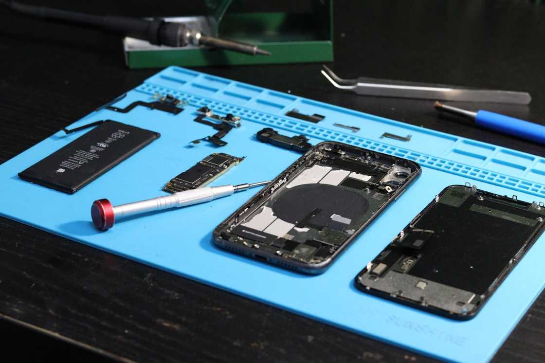 A disassembled smartphone parts laid out on a repair mat.