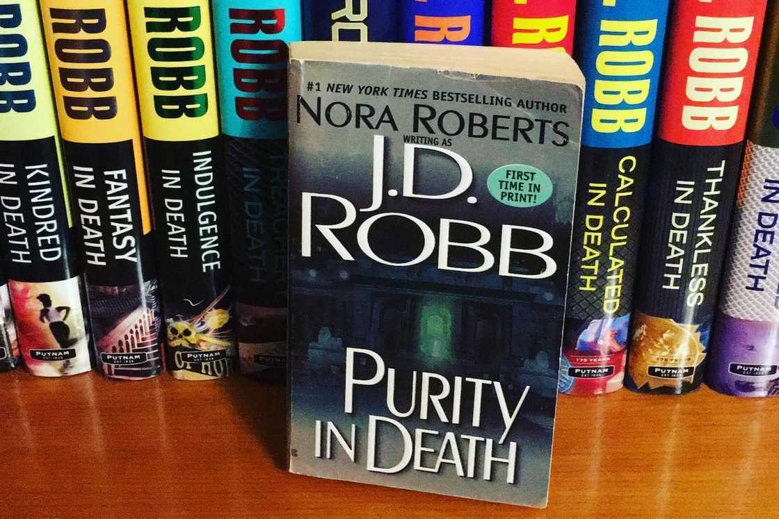 The Purity in Death book is on a wooden shelf