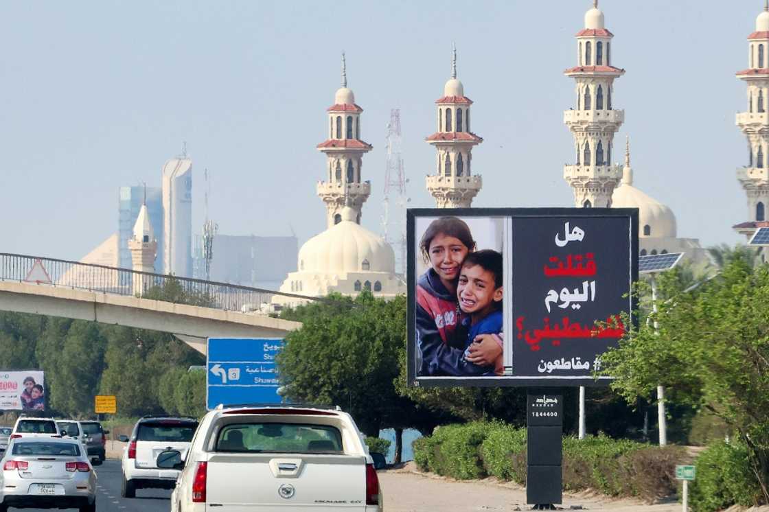 Cars drive past a billboard in Kuwait City showing Palestinian children and the slogan: "Have you killed a Palestinian today? #boycott"
