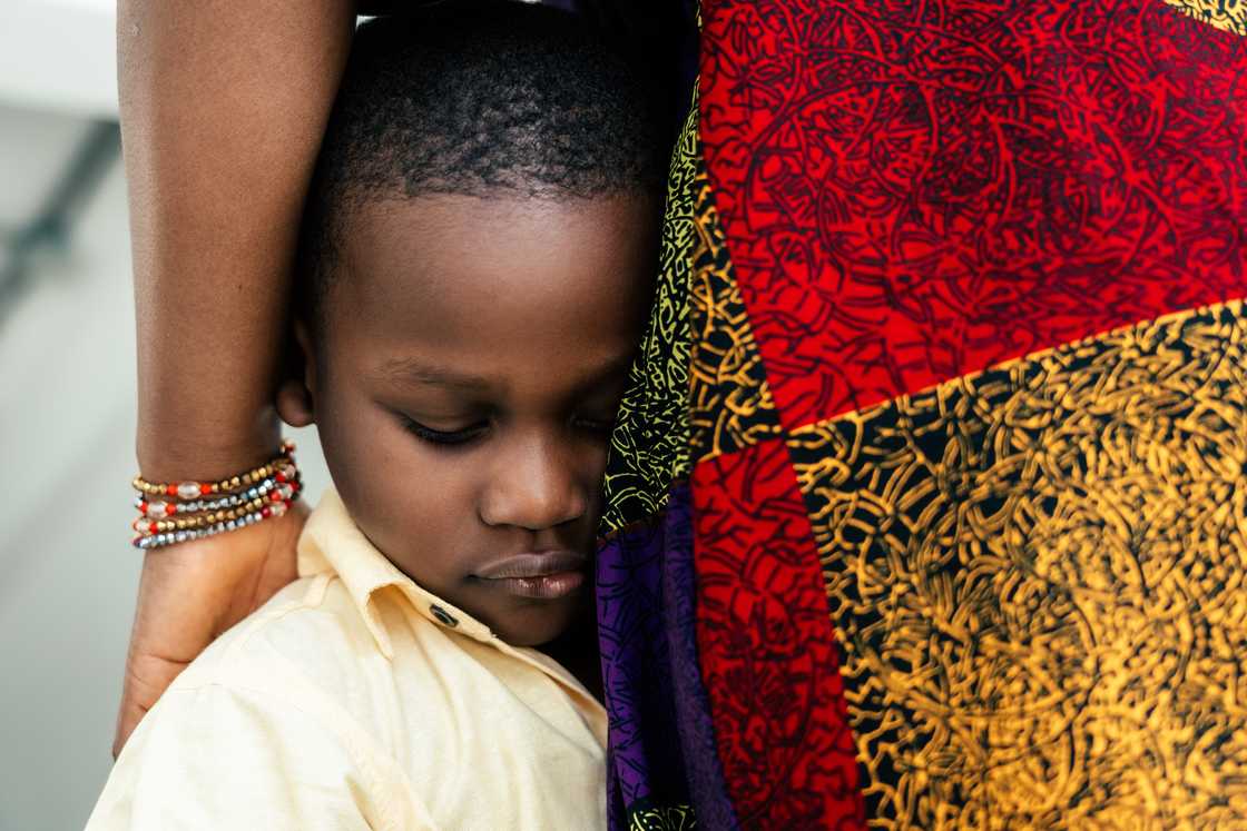 A scared boy holding his mom