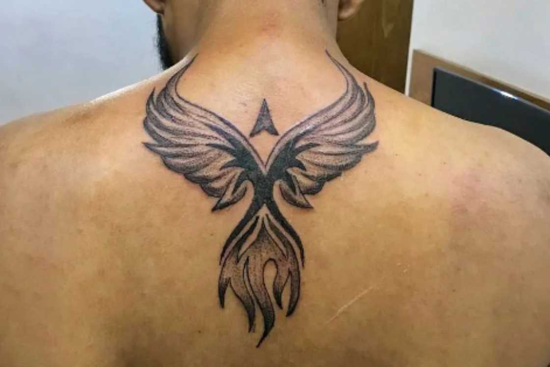 A man has a phoenix tattoo on his upper middle part A man has a phoenix tattoo on his upper middle part