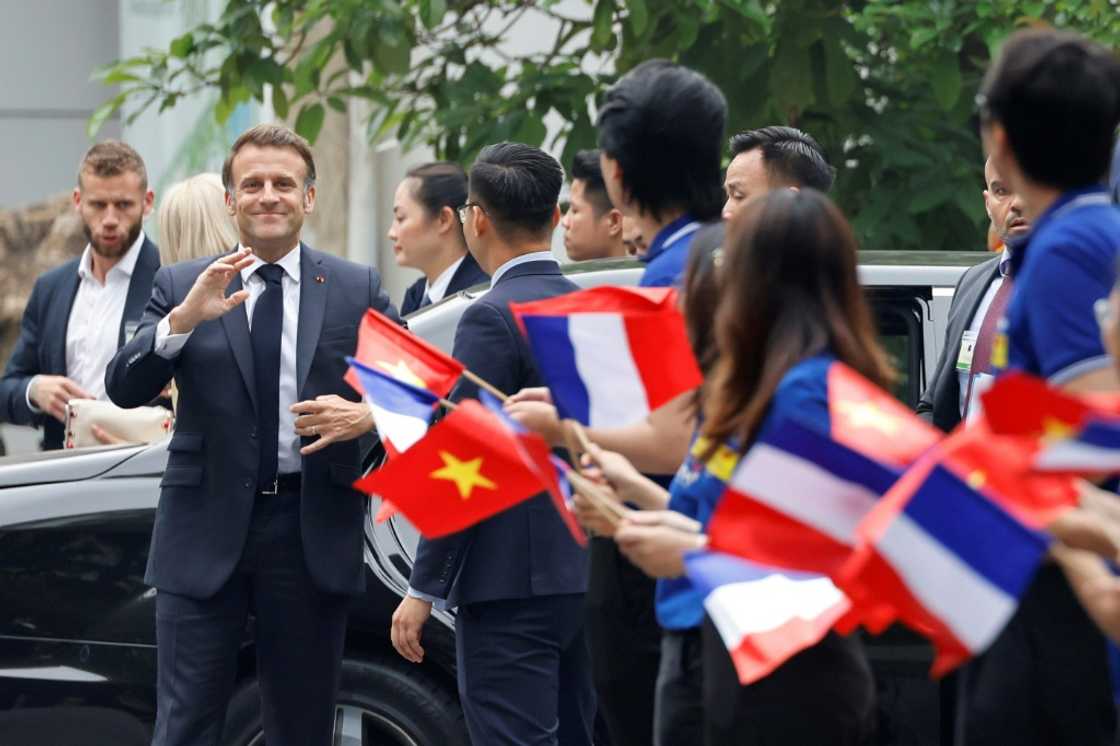 France's President Emmanuel Macron is greeted by flag waving university students in Hanoi