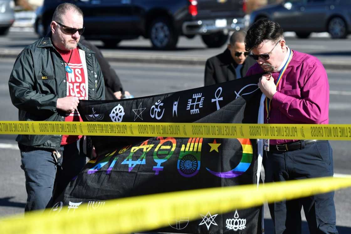 Michael I. Travis (left) and Dr. Michael R. Travis place a flag at a memorial for the shooting victims