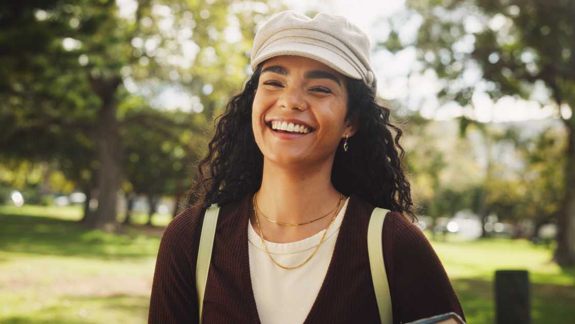 A young lady feeling refreshed as she walks in a pathway filled with trees