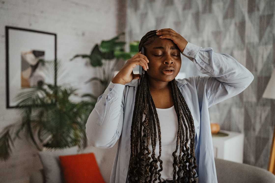 A worried woman holding her forehead while on a call