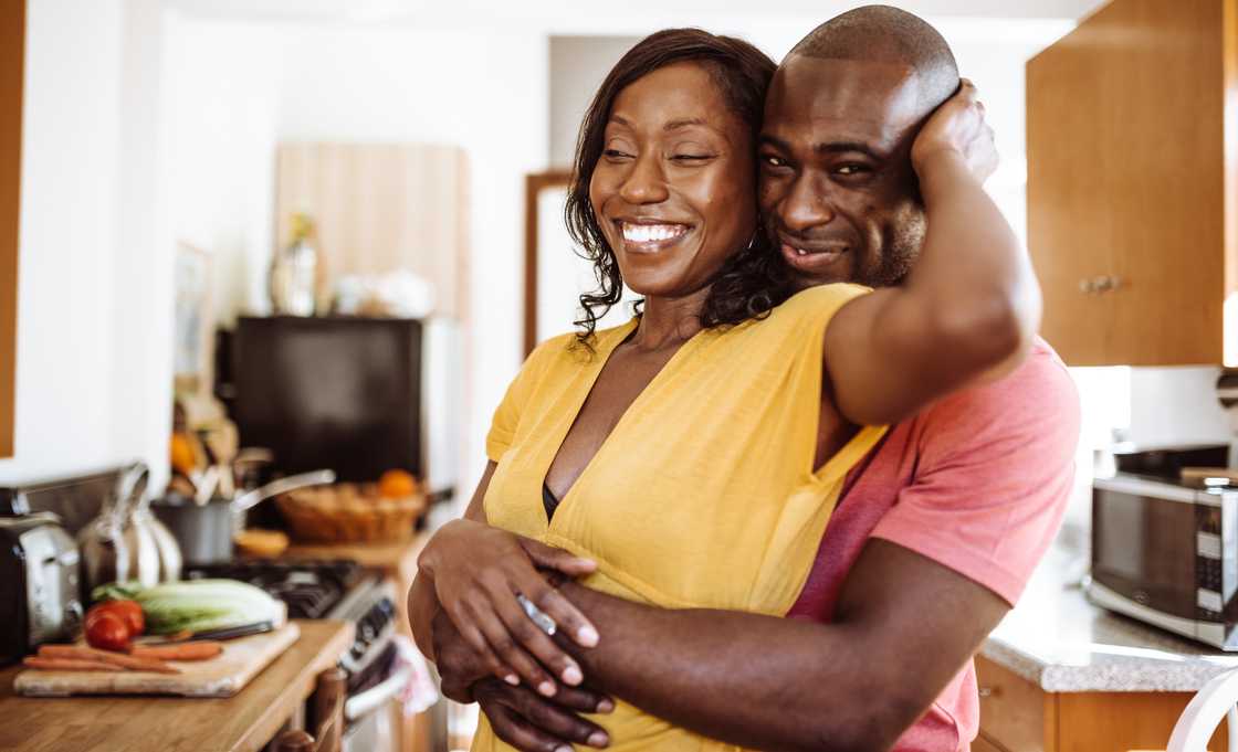 A happy couple in the kitchen are hugging