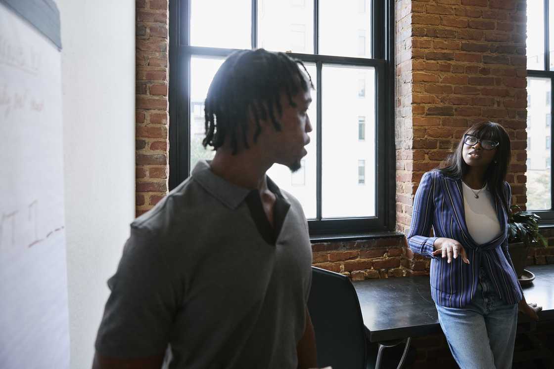 A female business professional discussing strategy with a male colleague A female business professional discussing strategy with a male colleague