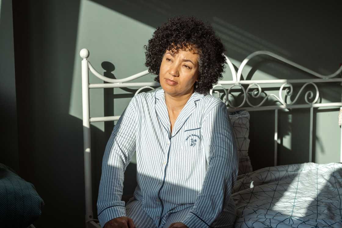 A thoughtfull woman sitting on a bed