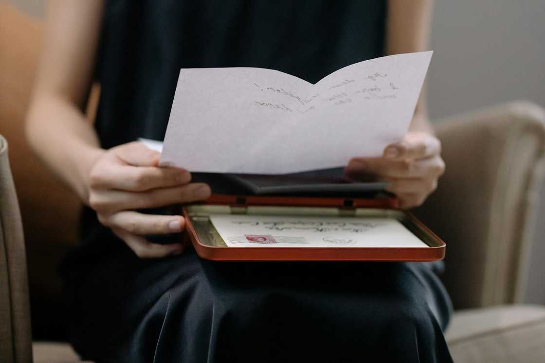 A woman reads a handwritten letter from a box.