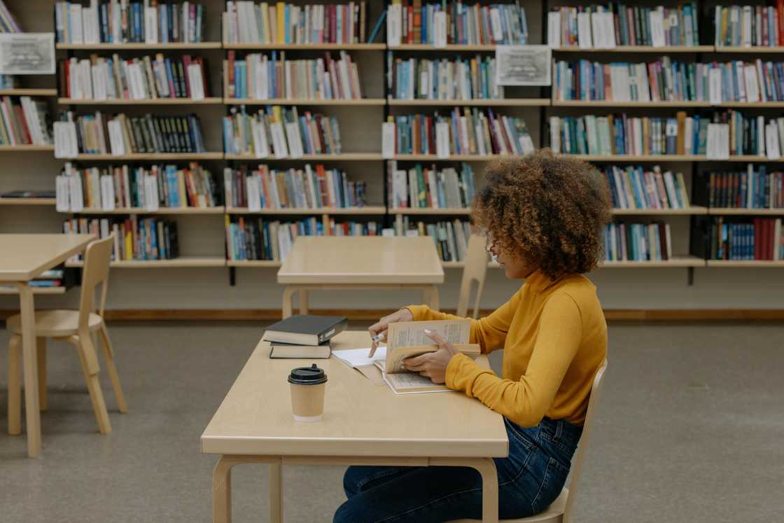 A young woman reading a book inside a library