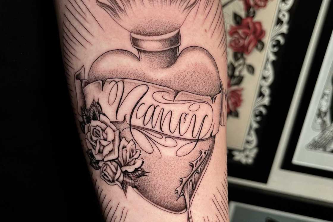 A forearm sacred heart tattoo with name