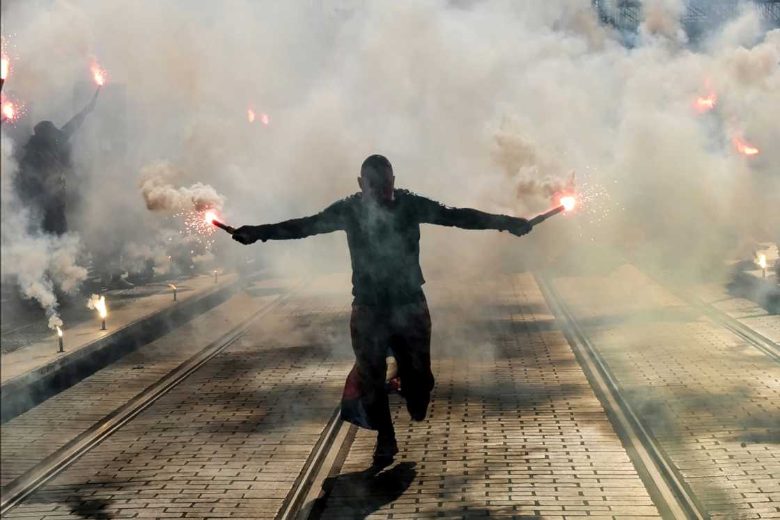 A protester holds burning flares during a demonstration in Nice A protester holds burning flares during a demonstration in Nice