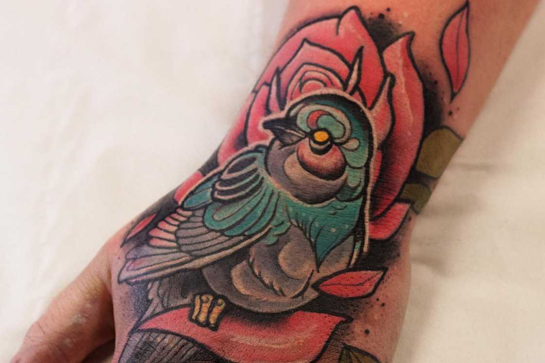 A bird on a pink neo-traditional rose tattoo A bird on a pink neo-traditional rose tattoo