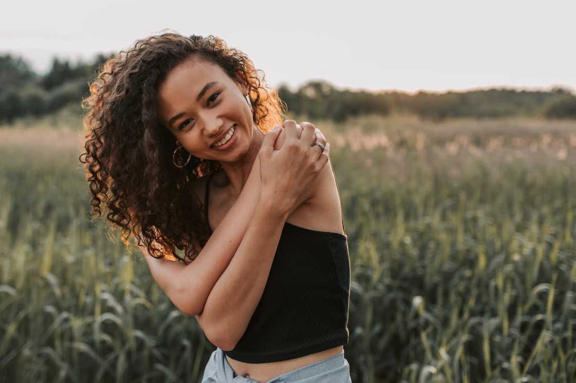 Smiling woman standing in a green field at sunset. Smiling woman standing in a green field at sunset.