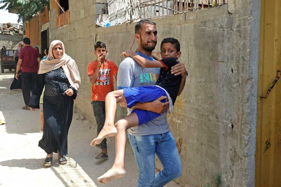 A Palestinian man carries an injured boy following an Israeli air strike, in Khan Yunis in the southern Gaza Strip A Palestinian man carries an injured boy following an Israeli air strike, in Khan Yunis in the southern Gaza Strip