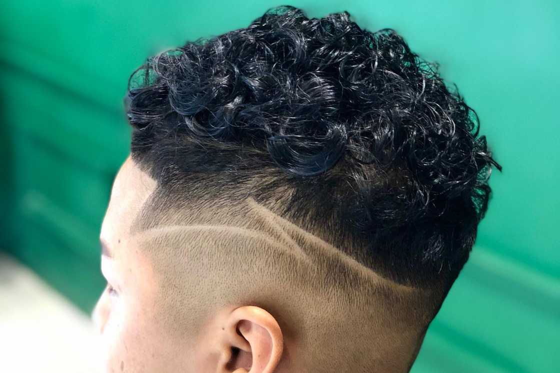 A man with temple fade with a curly top haircut