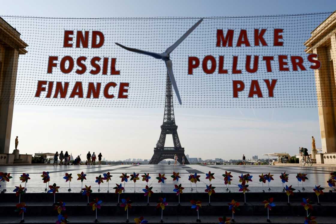 Activists demonstrate in Paris against fossil finance, with the Eiffel Tower in background, on June 21, 2023 Activists demonstrate in Paris against fossil finance, with the Eiffel Tower in background, on June 21, 2023