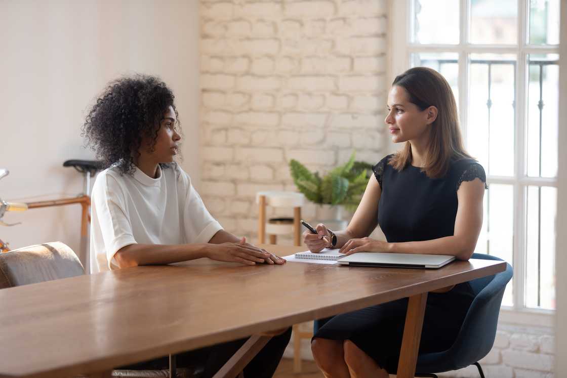 Two women discuss matters in an office.