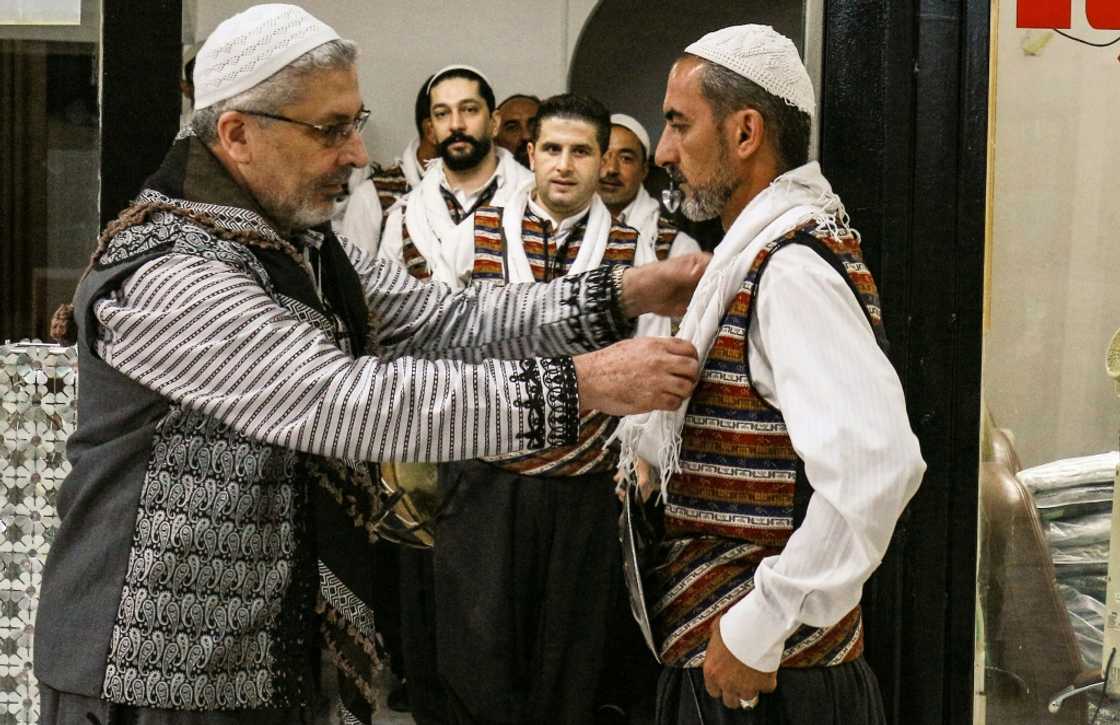 Moutaz Boulad (L), leader of the "Bab al-Hara" traditional Syrian "Arada" dance troupe, assists members as they gear up to perform Moutaz Boulad (L), leader of the "Bab al-Hara" traditional Syrian "Arada" dance troupe, assists members as they gear up to perform
