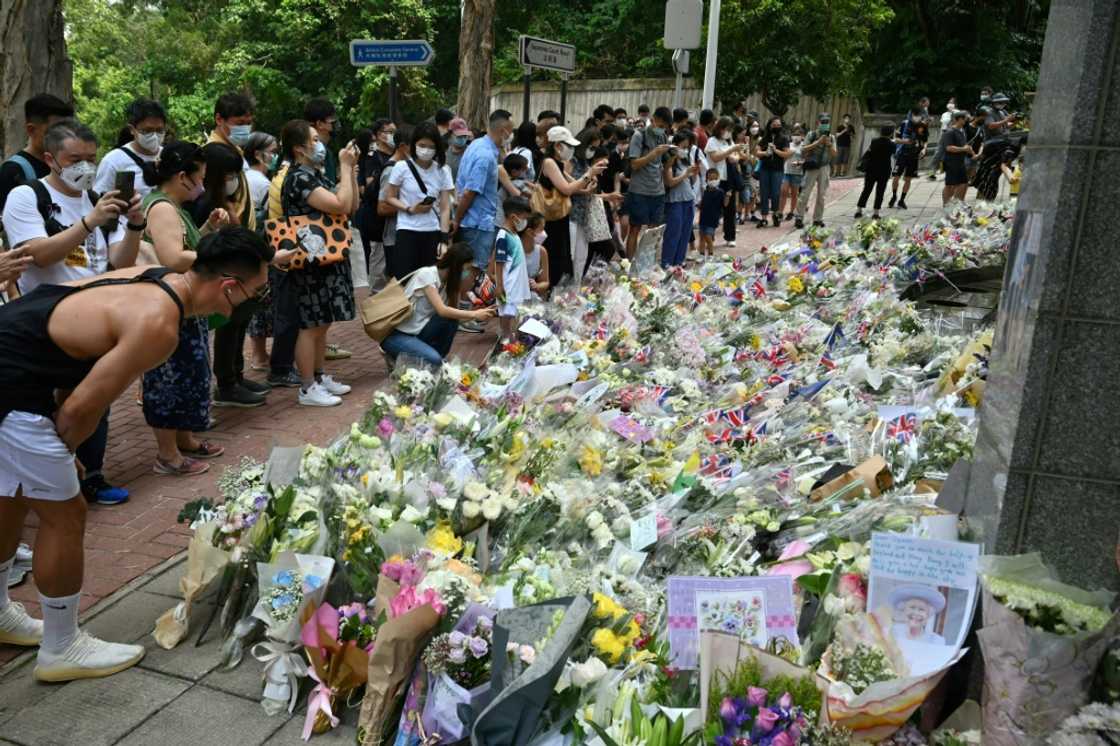 People gather next to flowers placed as a tribute to Queen Elizabeth outside the British consulate in Hong Kong People gather next to flowers placed as a tribute to Queen Elizabeth outside the British consulate in Hong Kong