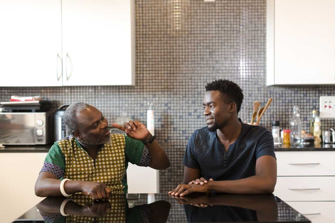 Adult child and father locked in a silent standoff in the kitchen. Adult child and father locked in a silent standoff in the kitchen.