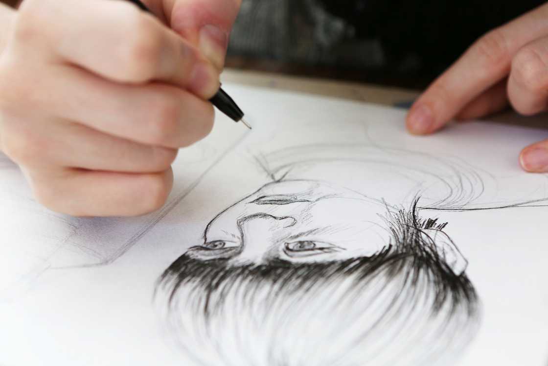 A person drawing someone on a paper A person drawing someone on a paper