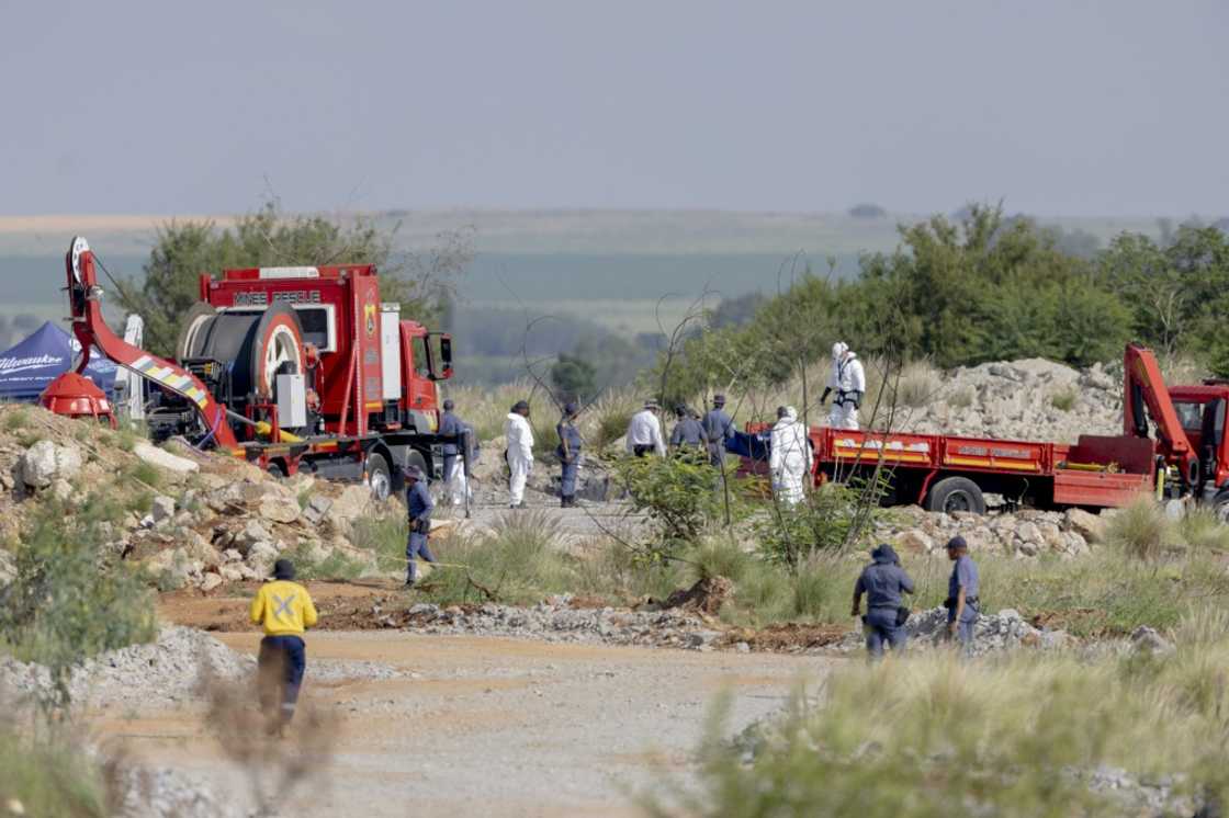 Rescuers and South African Police Service (SAPS) officers carry remains in blue body bags during the rescue operation