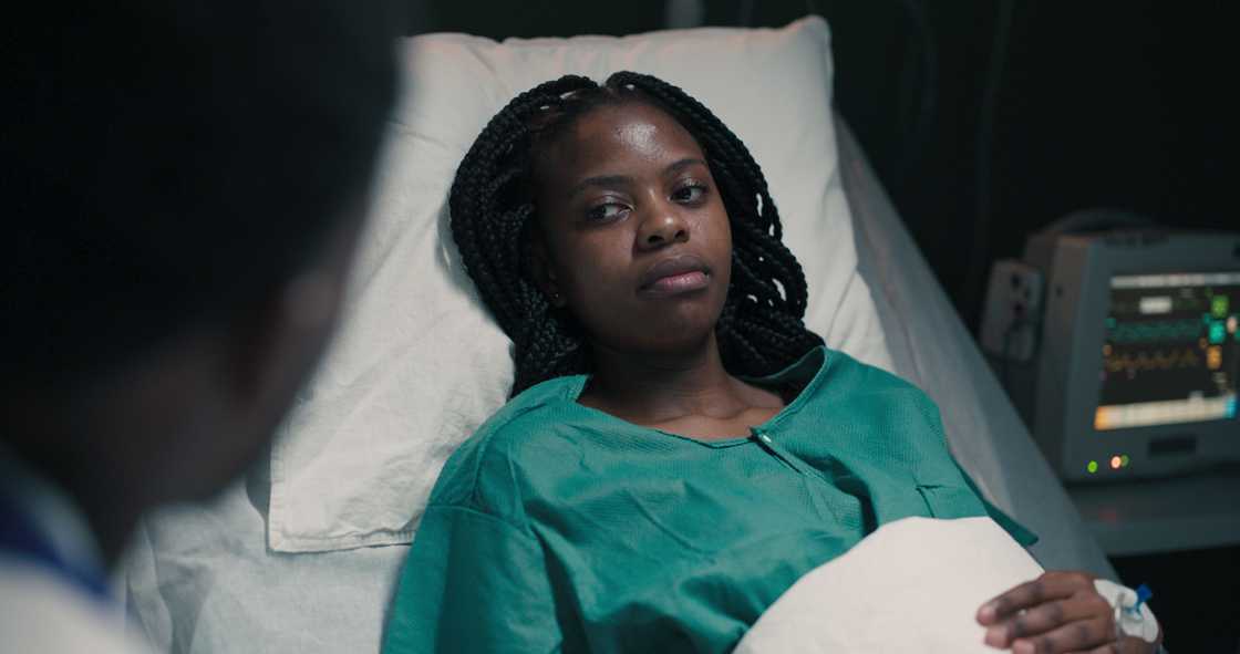 A woman rests on a bed with an IV drip. A woman rests on a bed with an IV drip.