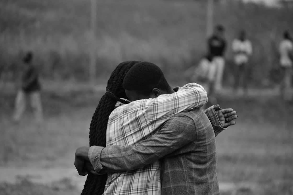 Two people embracing tightly in an emotional outdoor moment. Two people embracing tightly in an emotional outdoor moment.