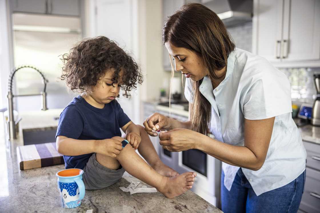 Mother putting a bandage on toddler