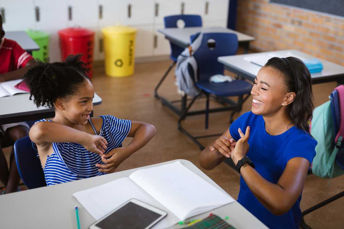 A young girl and teacher signing in class