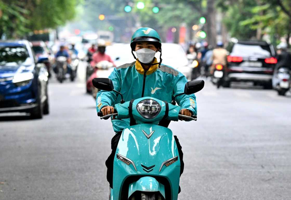 Motorbike taxi driver Phung Khac Trung rides his electric motorbike on a street in Hanoi